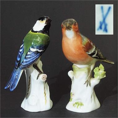 Zwei Vogelfiguren auf Baumstamm sitzend. 